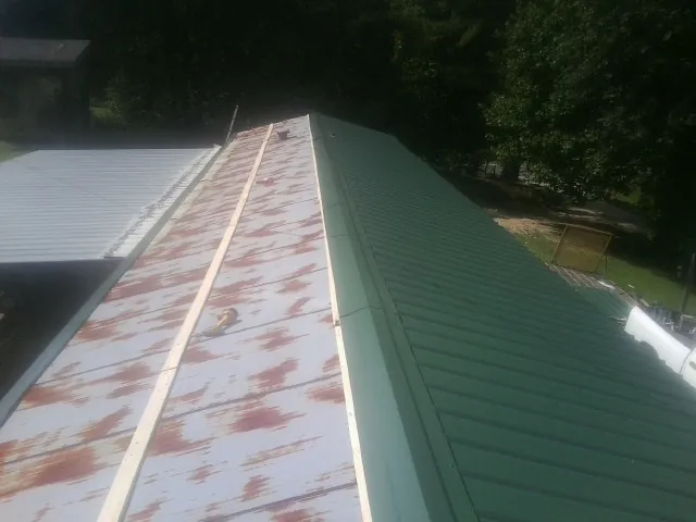 Old rusted panels beside newly installed green metal roofing — Wind Damage Roof Repair by Roofing Brothers in Warminster