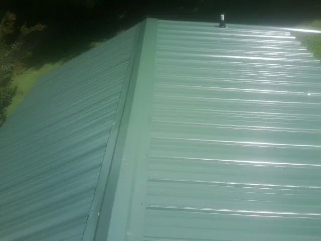 New green metal panels meeting at the ridge of a roof — Flat Roof Repair work by our crew in Warminster