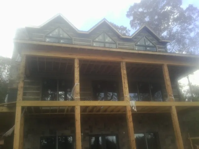 Dormers and porch framing on a large log home under construction — Roof Coating work by our crew in Warminster