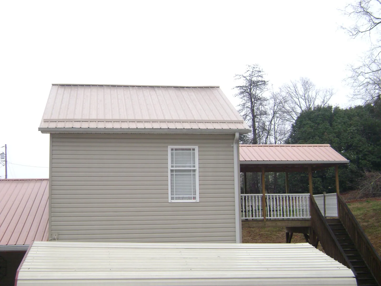 Tan metal roofs on a two story addition and attached porch, from a Roof Replacement job in Warminster