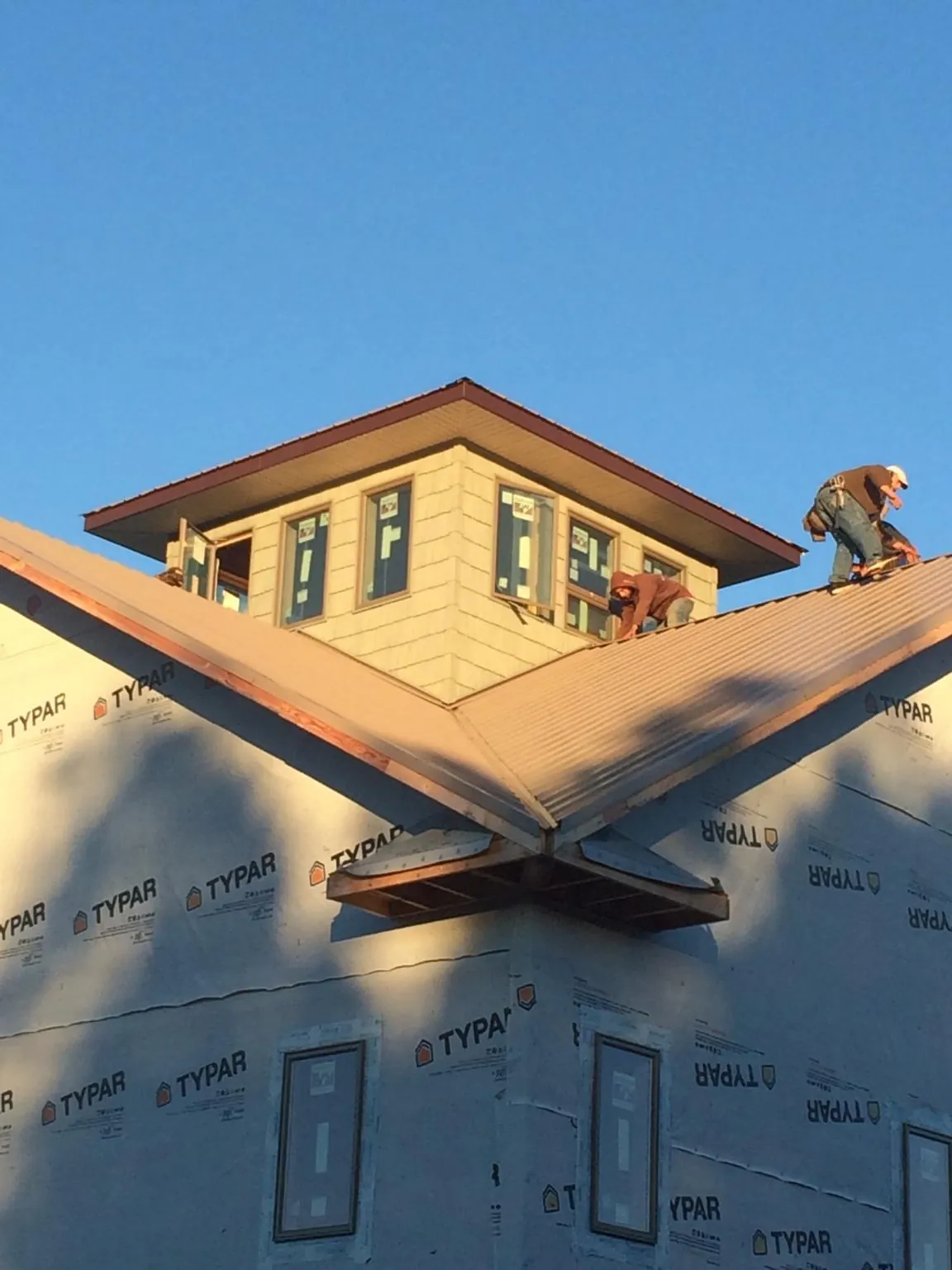 Roofers working around a rooftop cupola on a new metal roof at sunset — Roof Waterproofing in Warminster by Roofing Brothers